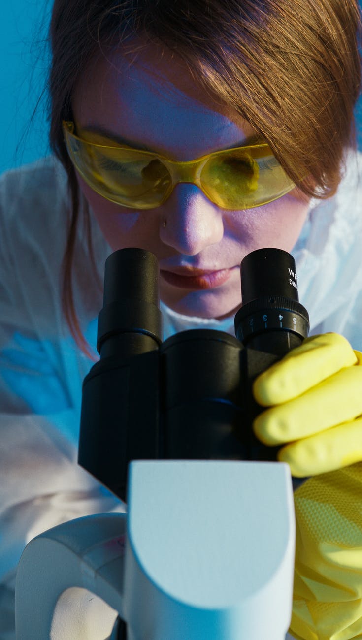photo of woman looking through microscope